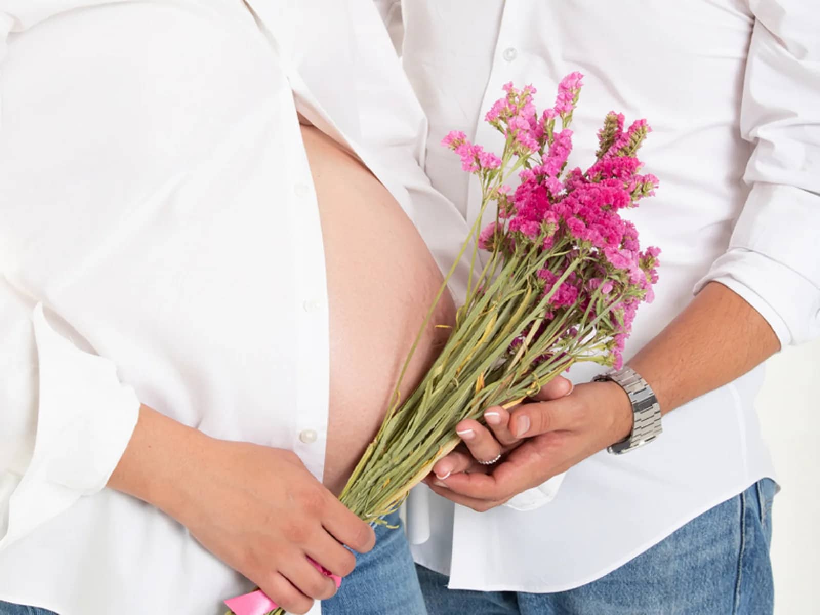 Pareja sosteniendo un ramo sobre la barriga