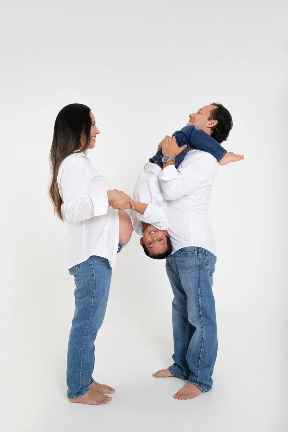 Papá levantando al hijo frente a la mamá embarazada