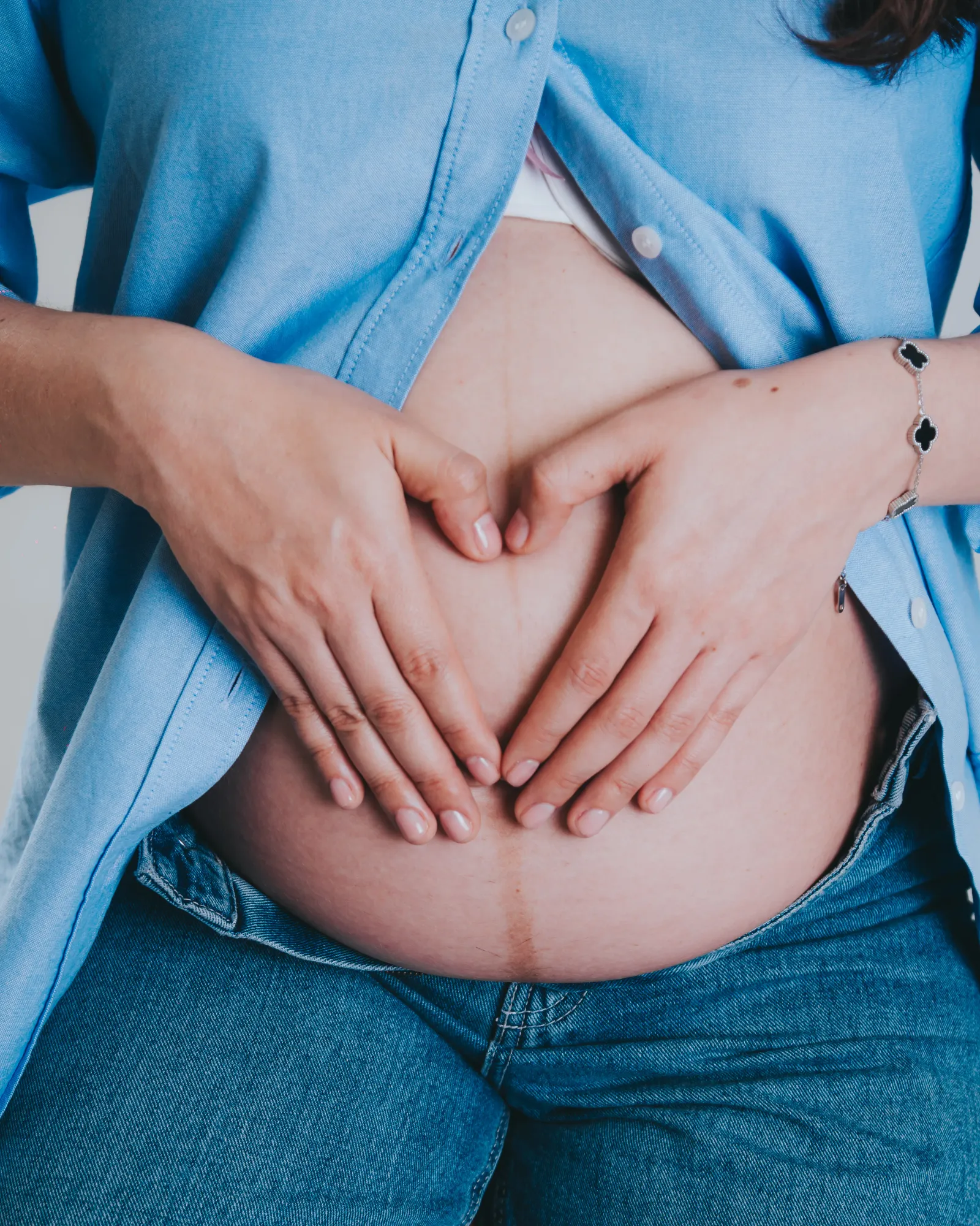 Manos en forma de corazón sobre barriga